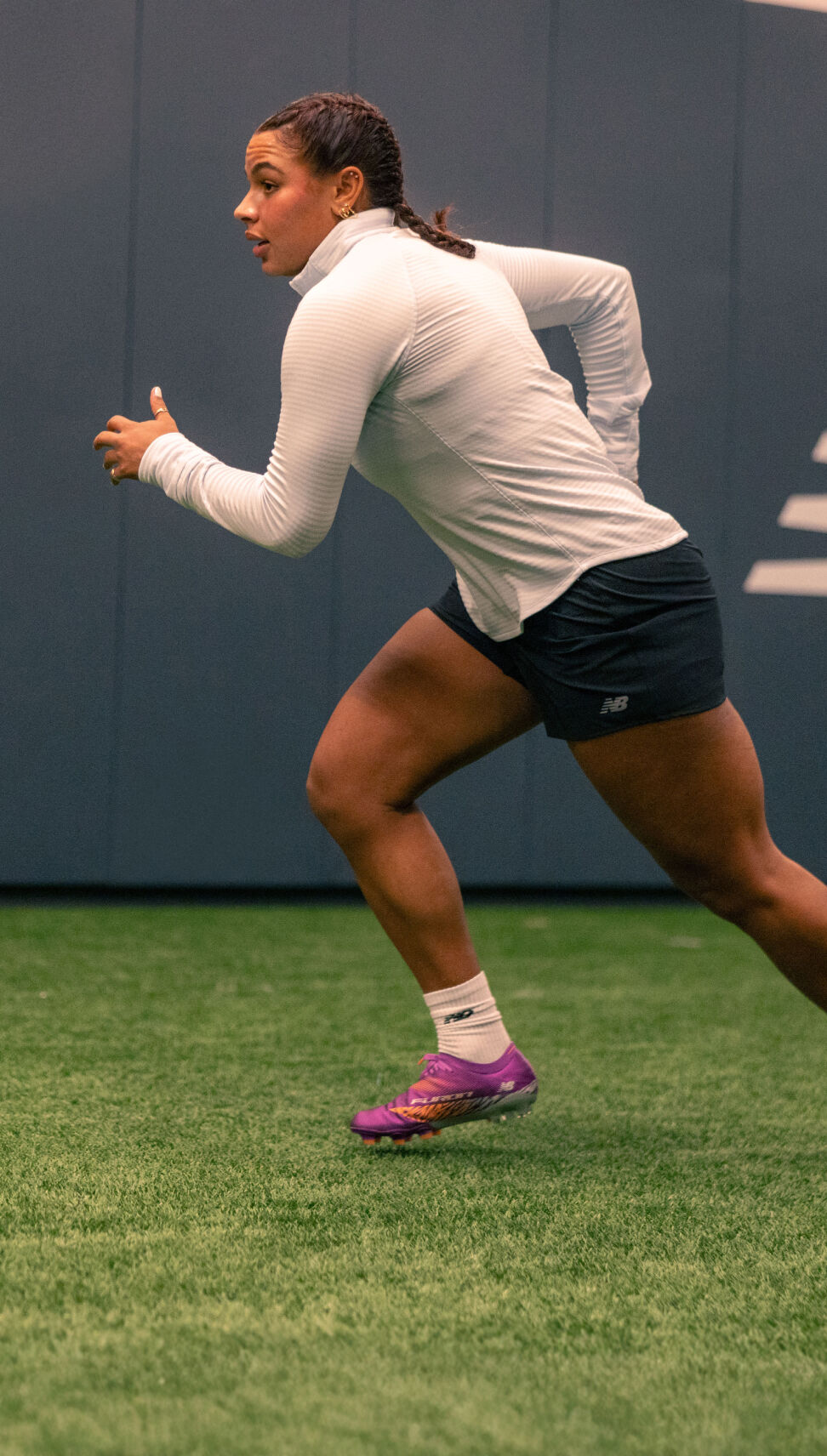 Young athlete running for a ball inside the training facility. 