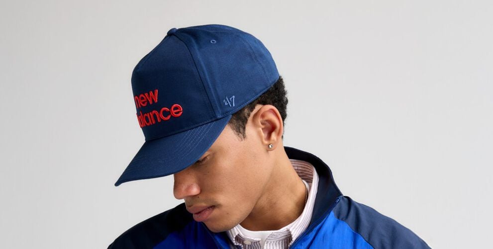 A close-up shot of a male looking to the side while wearing a navy &lsquo;47 hat.    