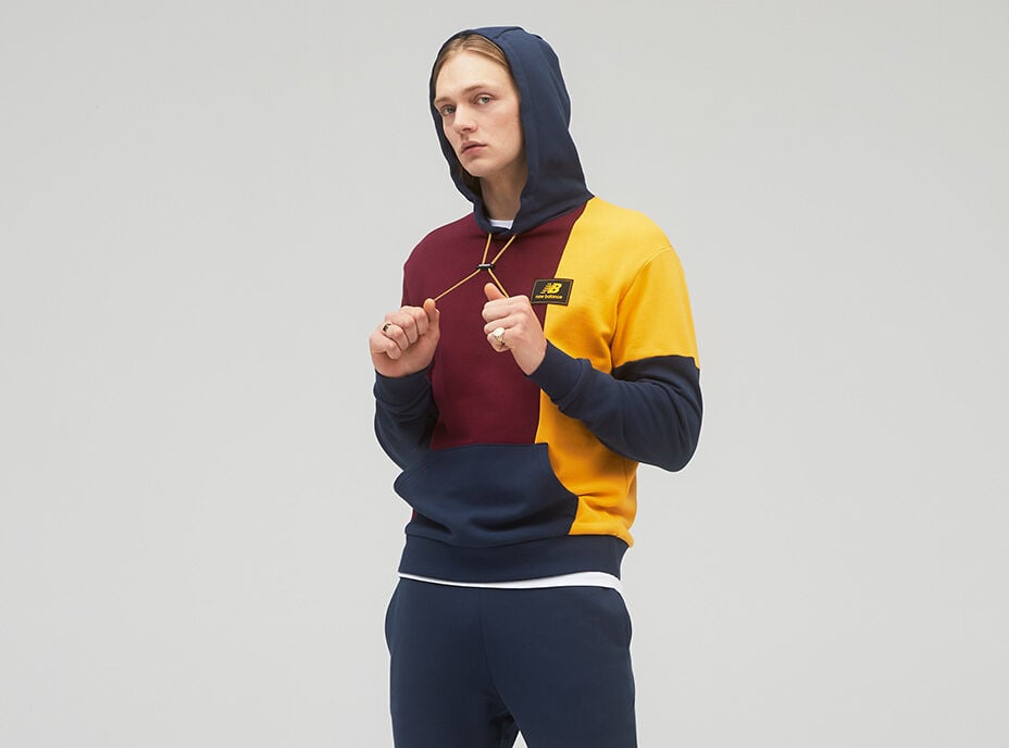 oung man wearing maroon, dark blue and yellow hoodie while pulling on the strings. 