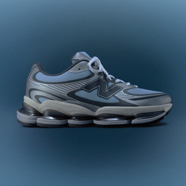 The ABZORB 2000 New Balance sneaker in a side profile in light chrome blue and silver metallic over a blue radial gradient background. 