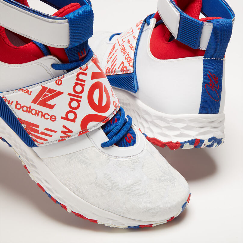 Cropped upper view of a white shoe with red and blue accents, on a light grey background