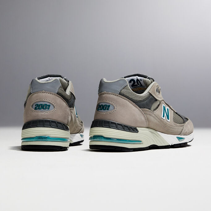A ¾ angle studio shot of the heels of a pair of women’s grey NB 991 sneakers