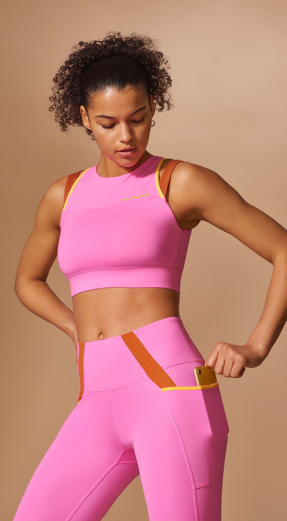 Waist-up crop of a woman posing in a matching pink set of a NB Fuel Bra and NB Shape Shield 7/8 High Rise Pocket Tights