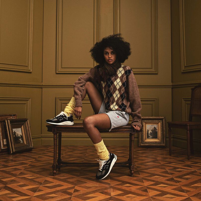 A woman sitting on a bench in a beautiful indoor environment wearing New Balance MADE in USA apparel and footwear.