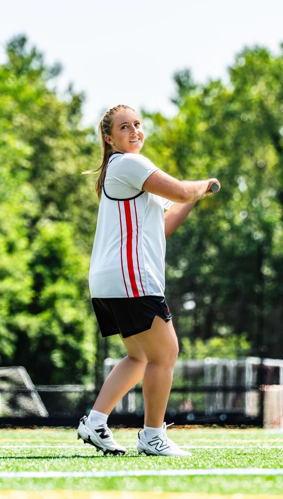 Lacrosse athlete in a white jersey shooting her shot. 