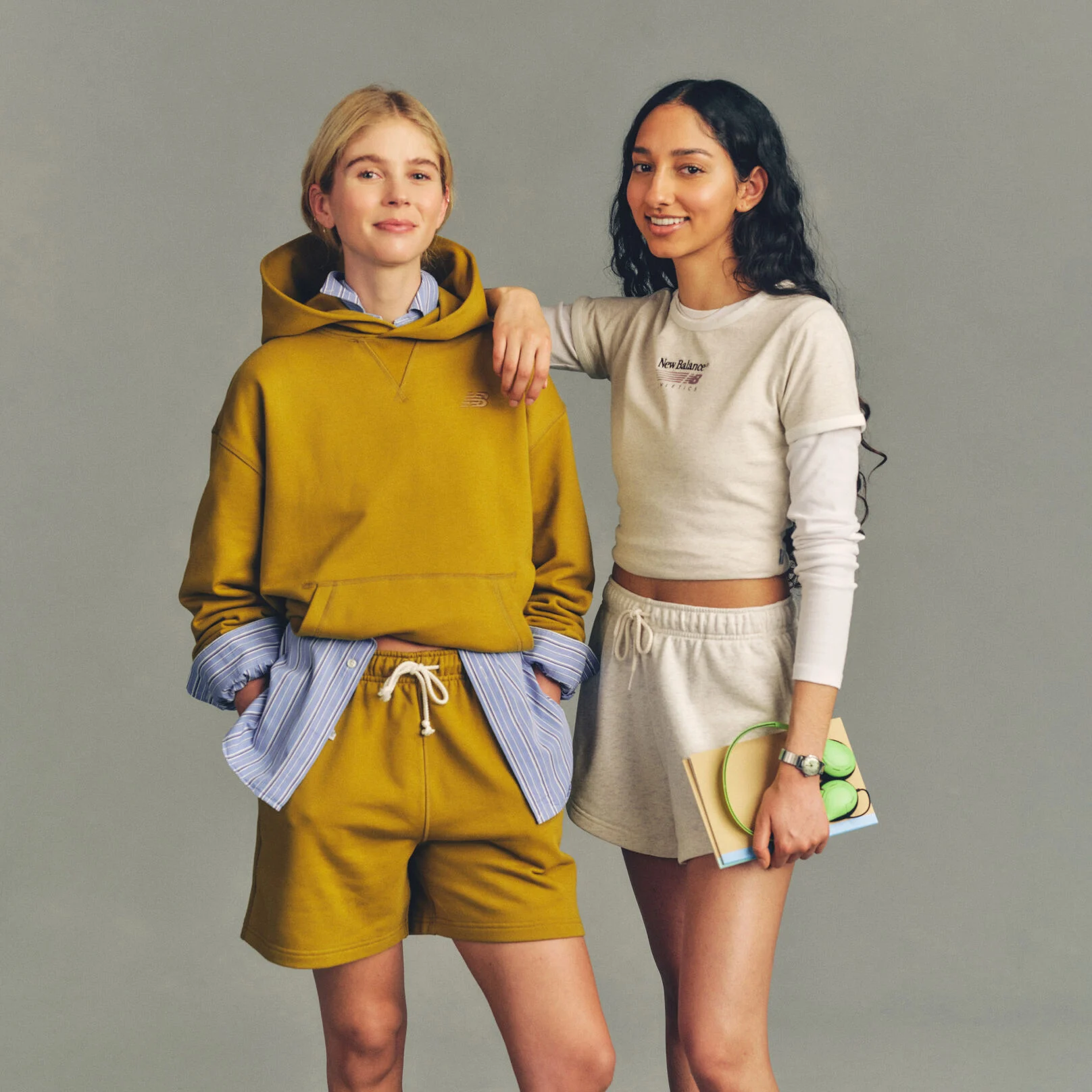 Imagen de estudio de dos personas situadas sobre un fondo gris claro sencillo, vestidas con ropa deportiva informal.