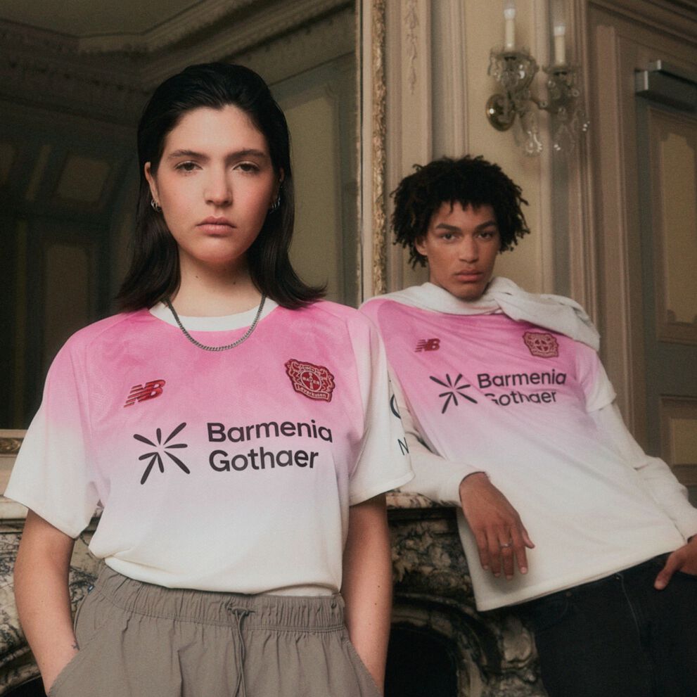 Pareja joven con camisetas de fútbol rosas apoyada en un espejo.