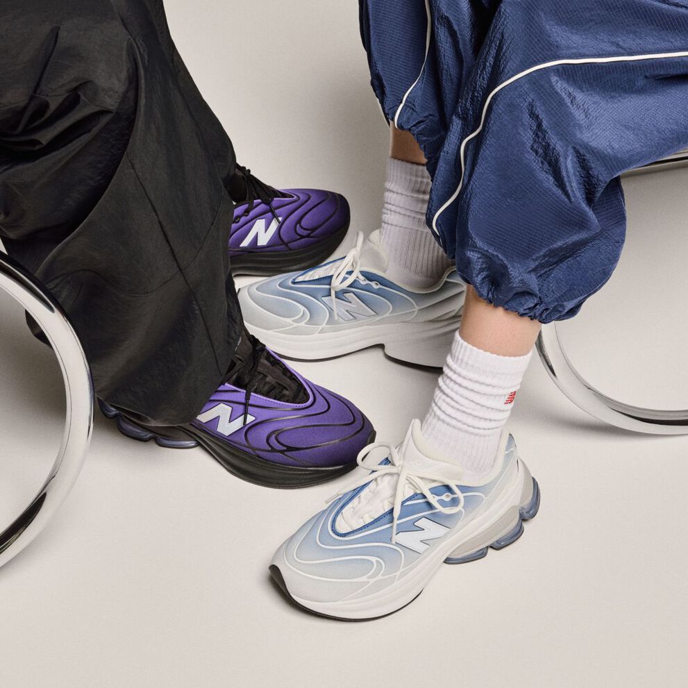 Knee-down view of two people wearing sneakers on a beige background. 