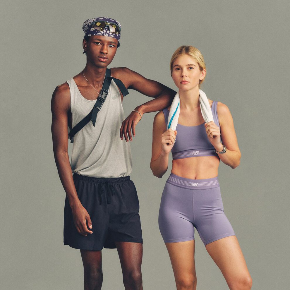 Two people stand side by side against a plain light gray studio background, wearing athletic apparel.