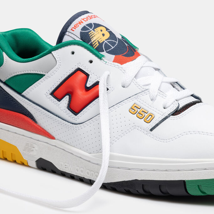Retro white, orange and green basketball shoe facing the right on a grey background.