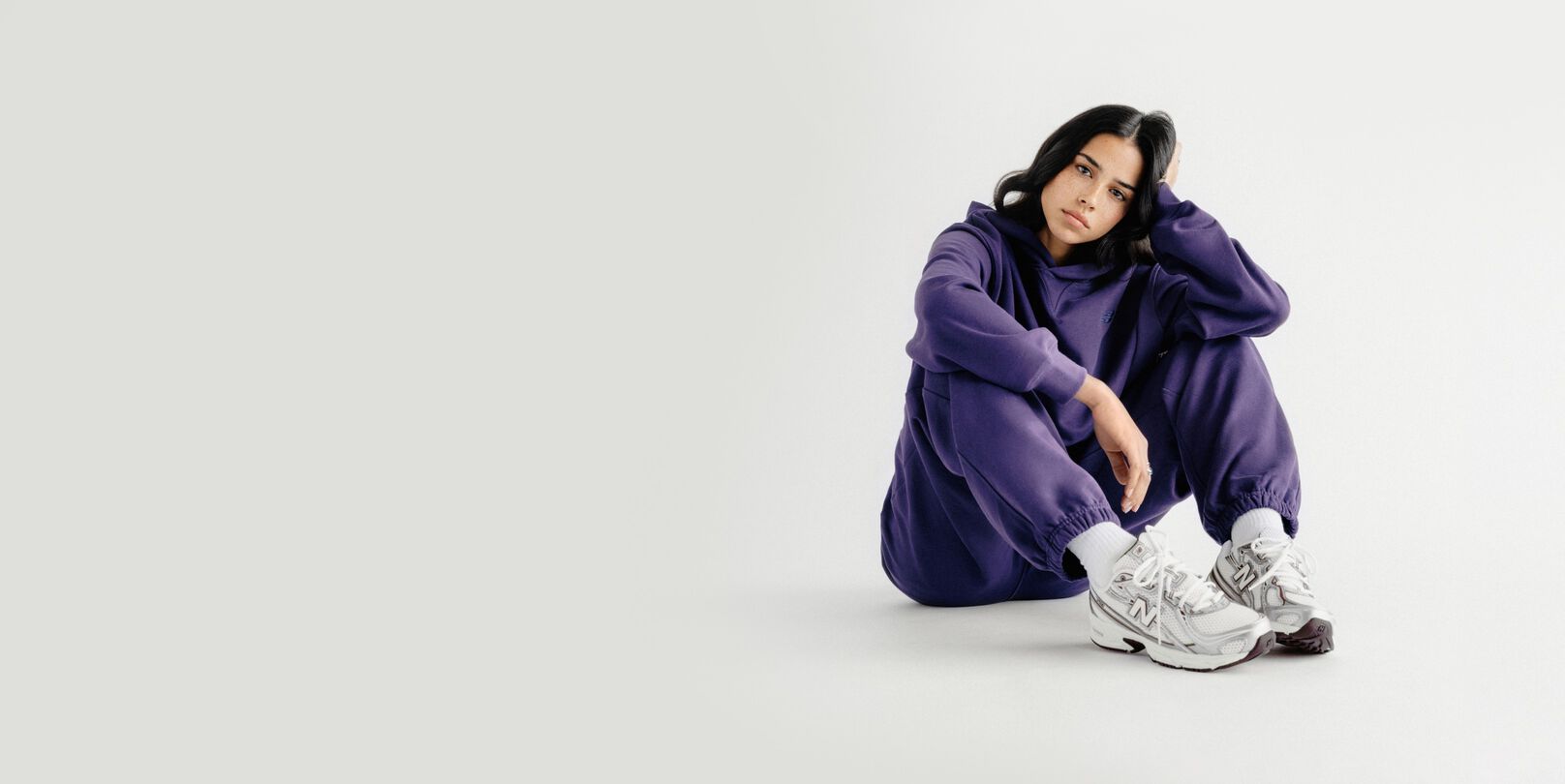 A woman sitting on a grey studio backdrop