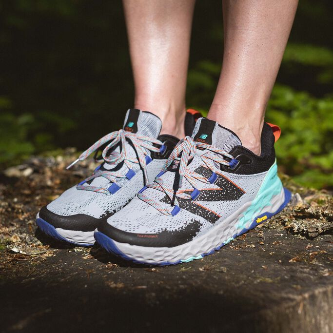 Woman standing on tree stump in gray Fresh Foam Hierro trail shoes