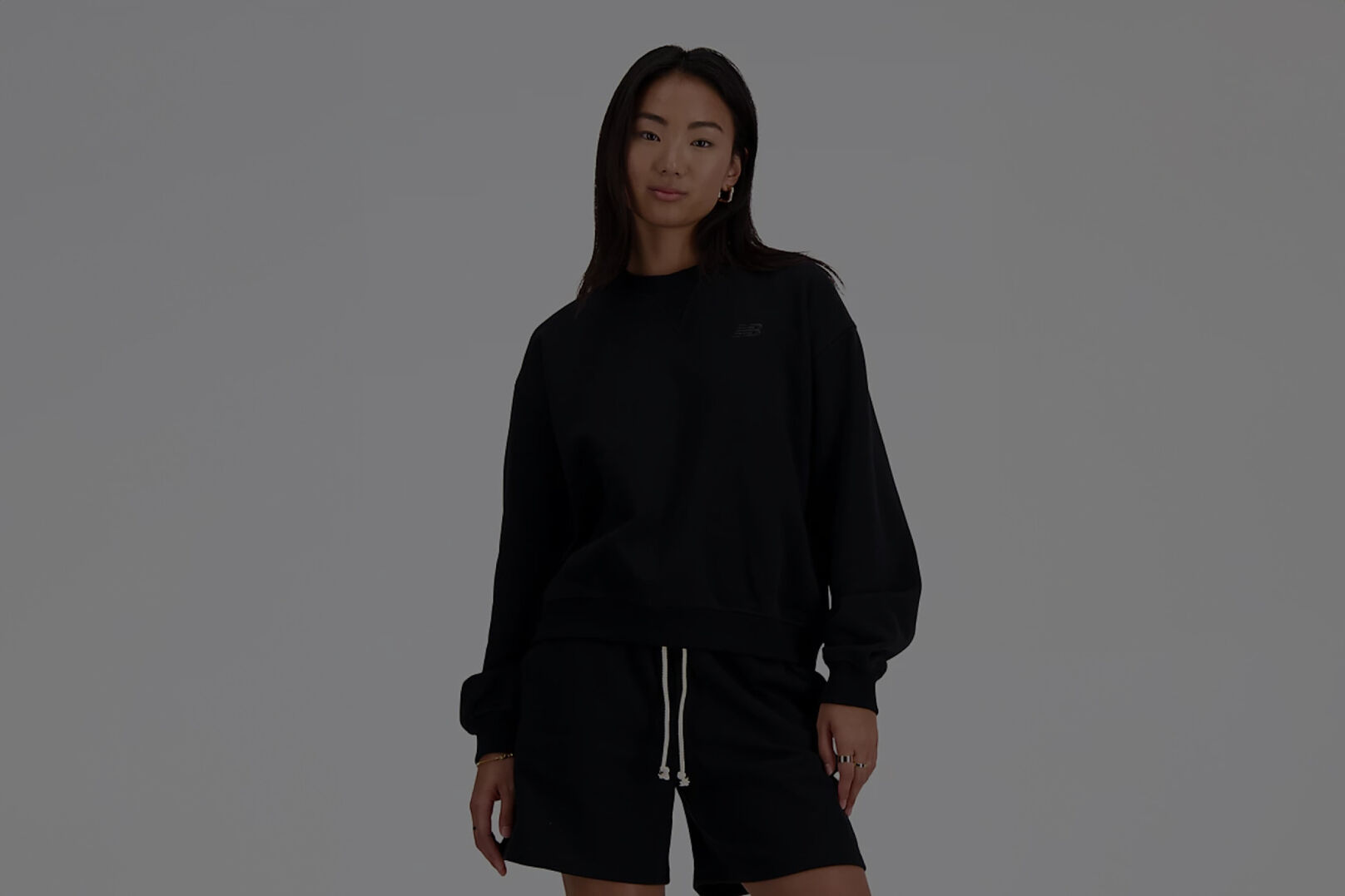 Woman in long sleeve black New Balance shirt and matching black shorts. 