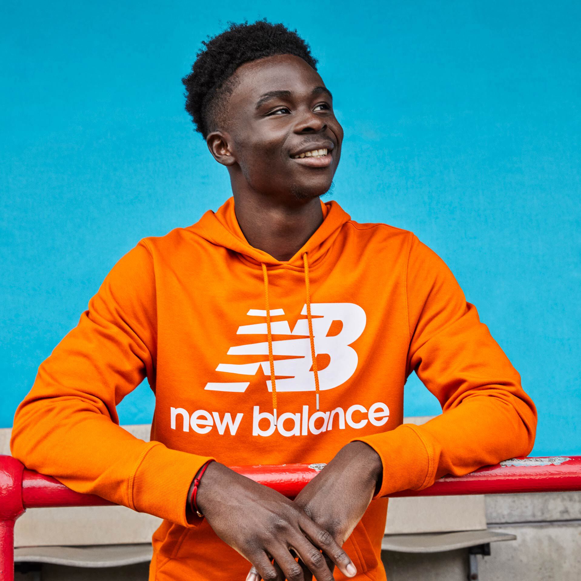 Bukayo Saka thigh up shot smiling leaning on handrail