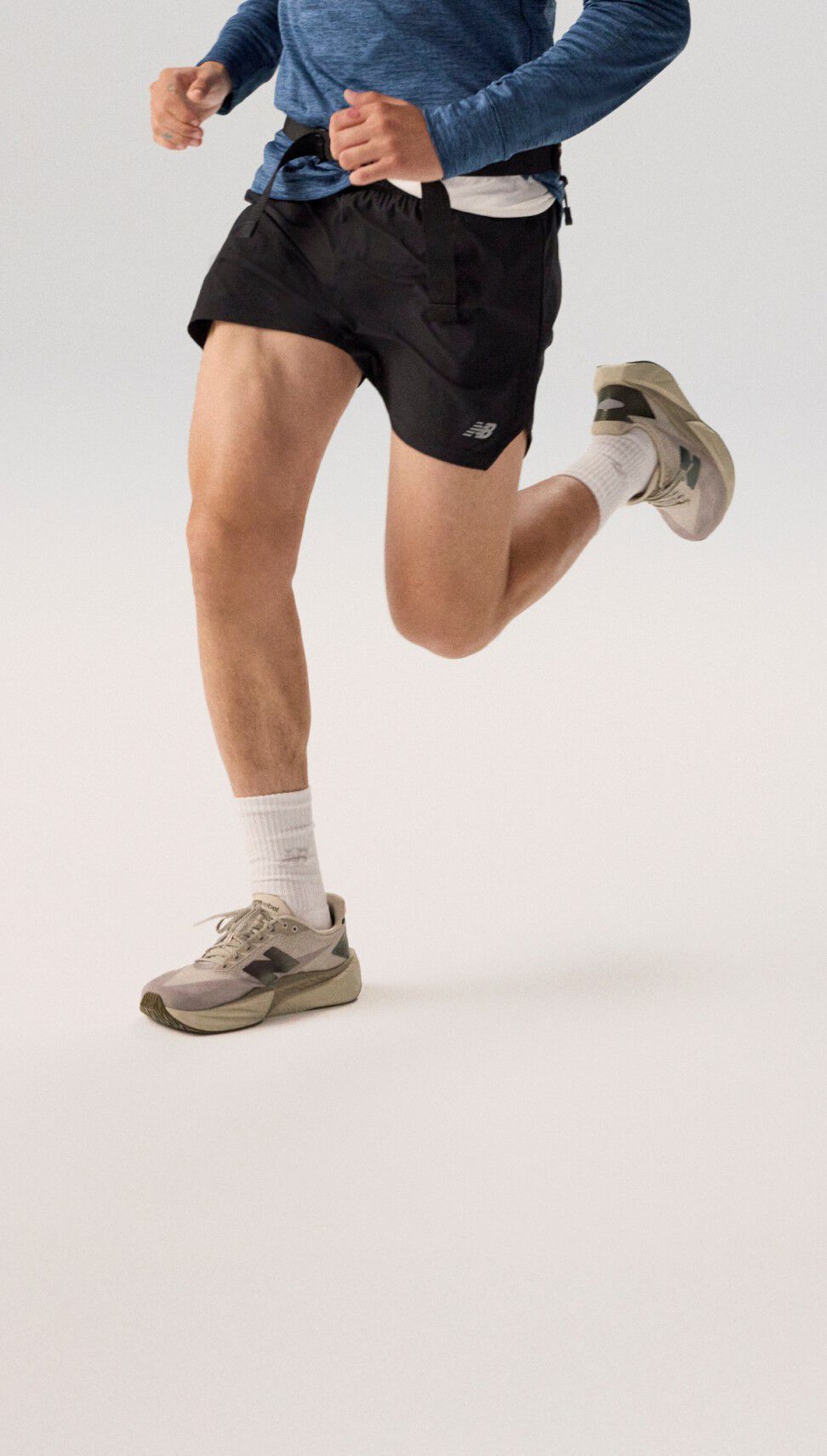Joven corriendo con una sudadera con capucha azul marino sobre un fondo gris.