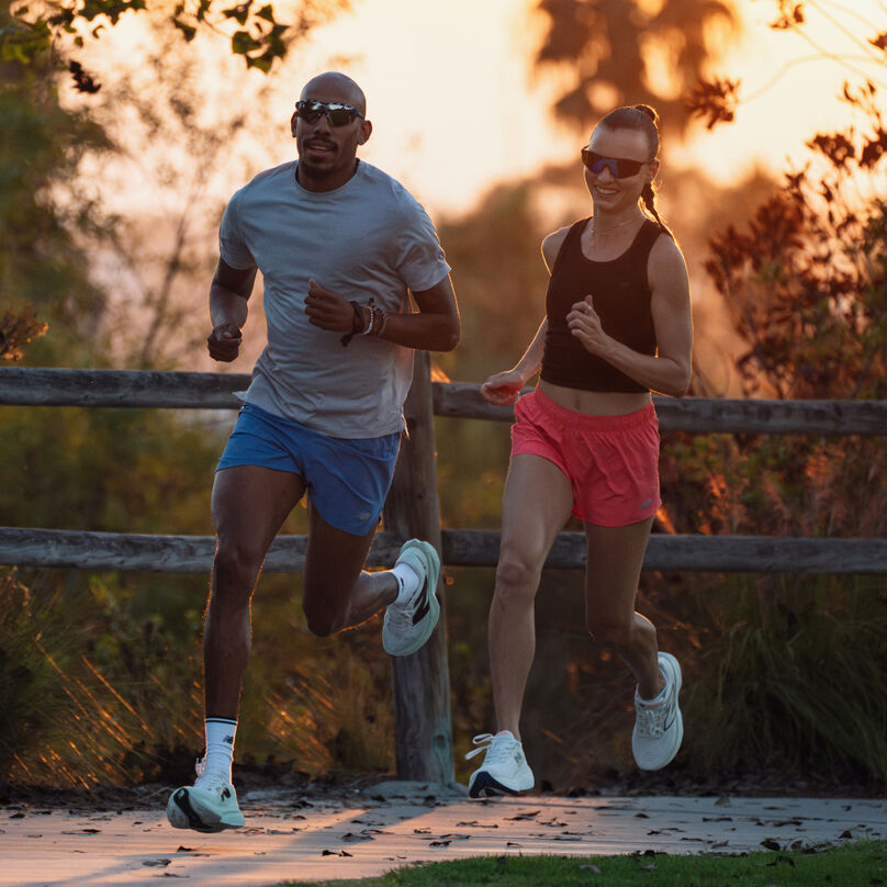 Young couple running on a sidewalk at dusk.