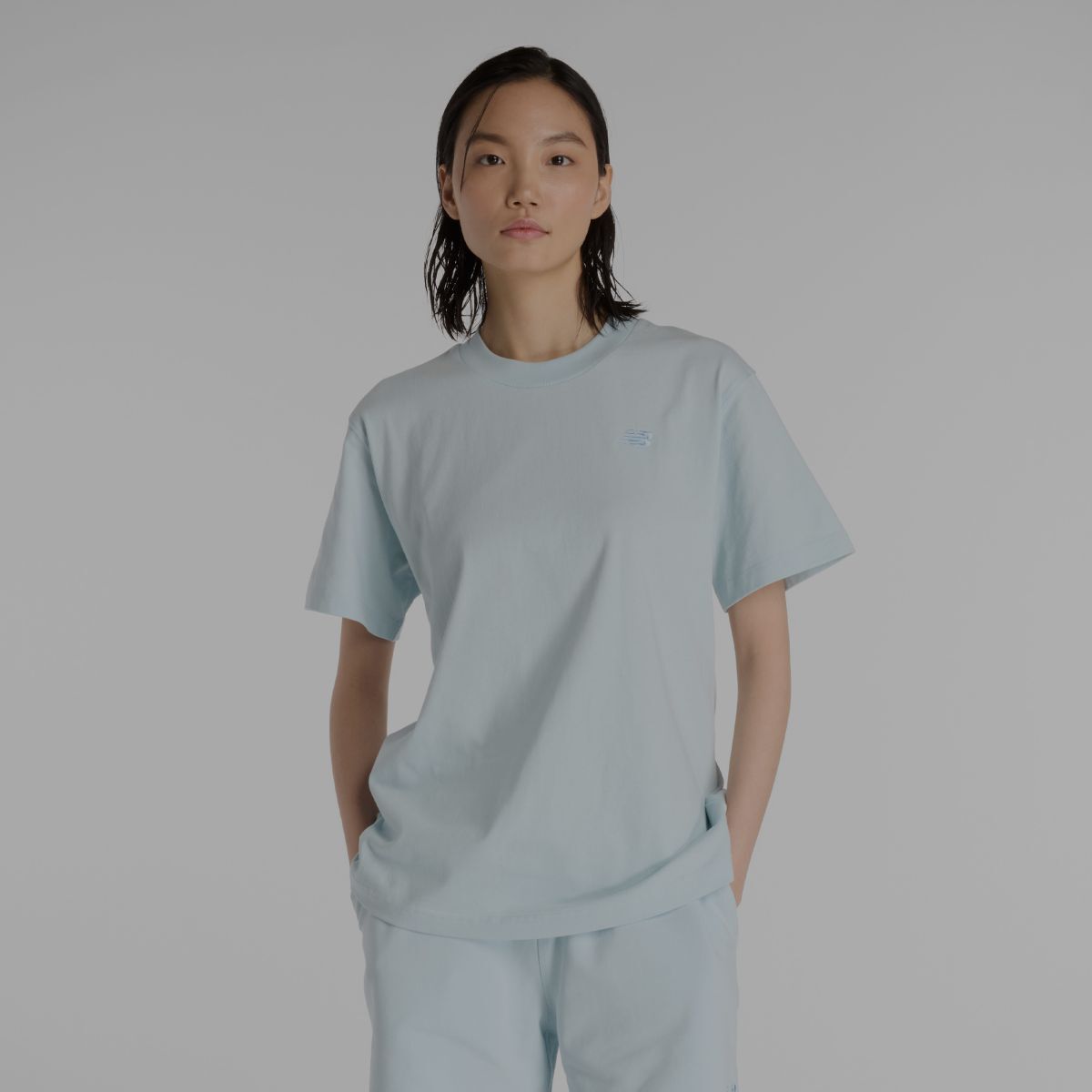 A woman wearing a light blue New Balance shirt.