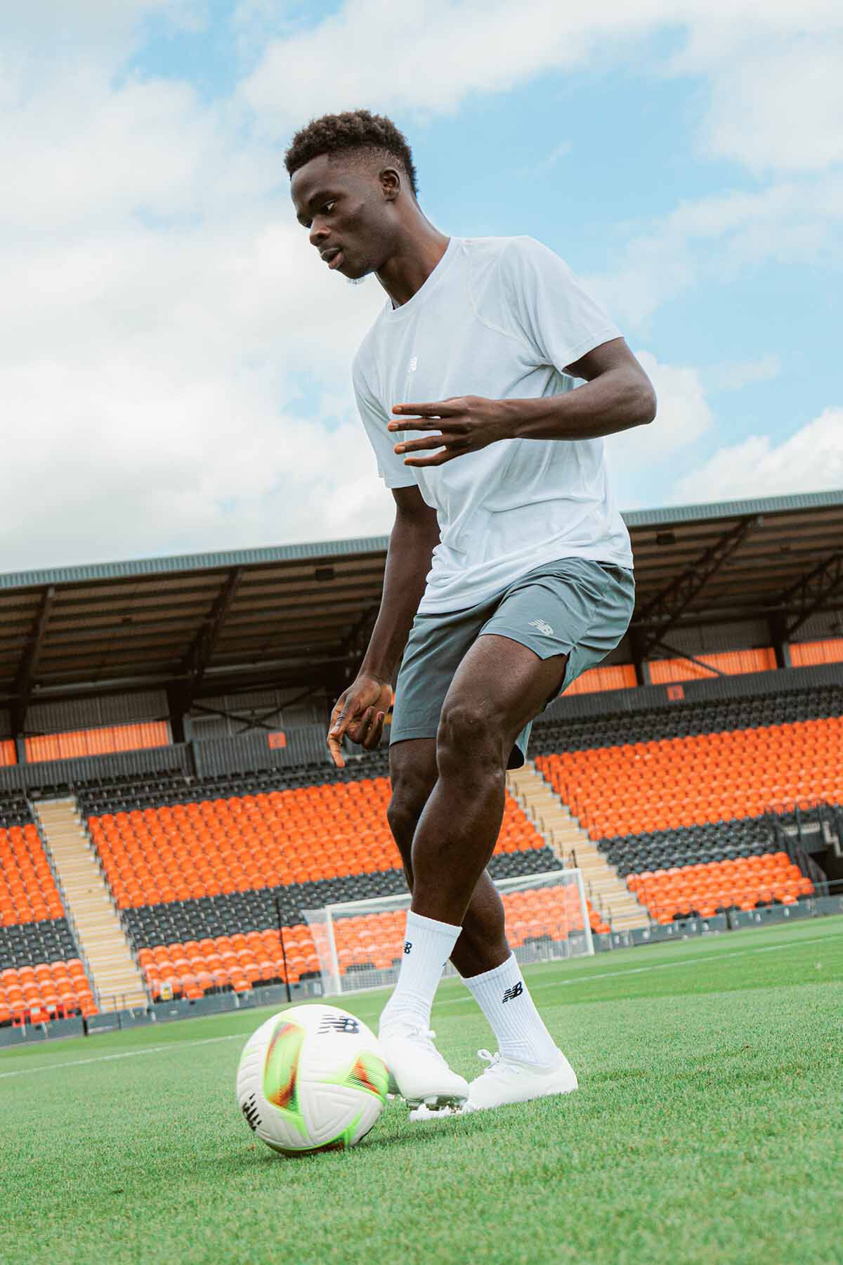 Bukayo Saka playing soccer on a field outdoors.