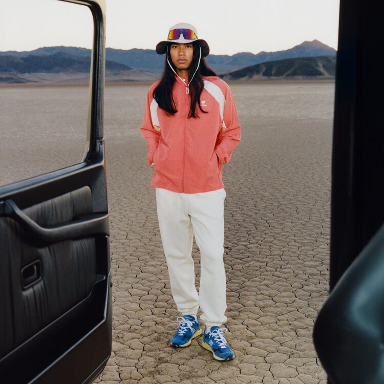 Man wearing a bucket hat and an orange jacket with his hands in his jacket pockets. 