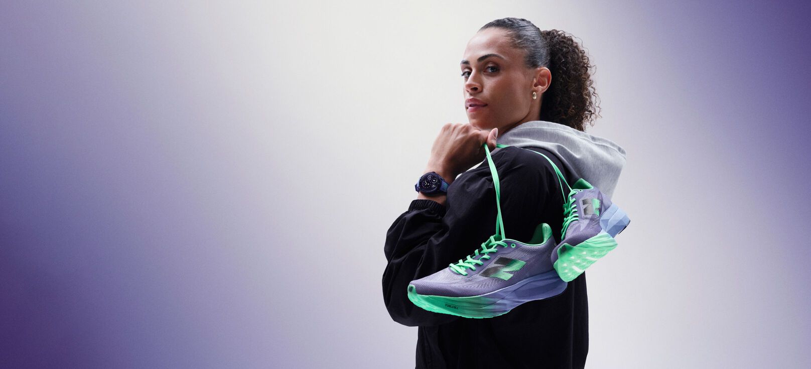 Sydney McLaughlin-Levrone sosteniendo un par de zapatillas sobre el hombro y mirando hacia el espectador. 