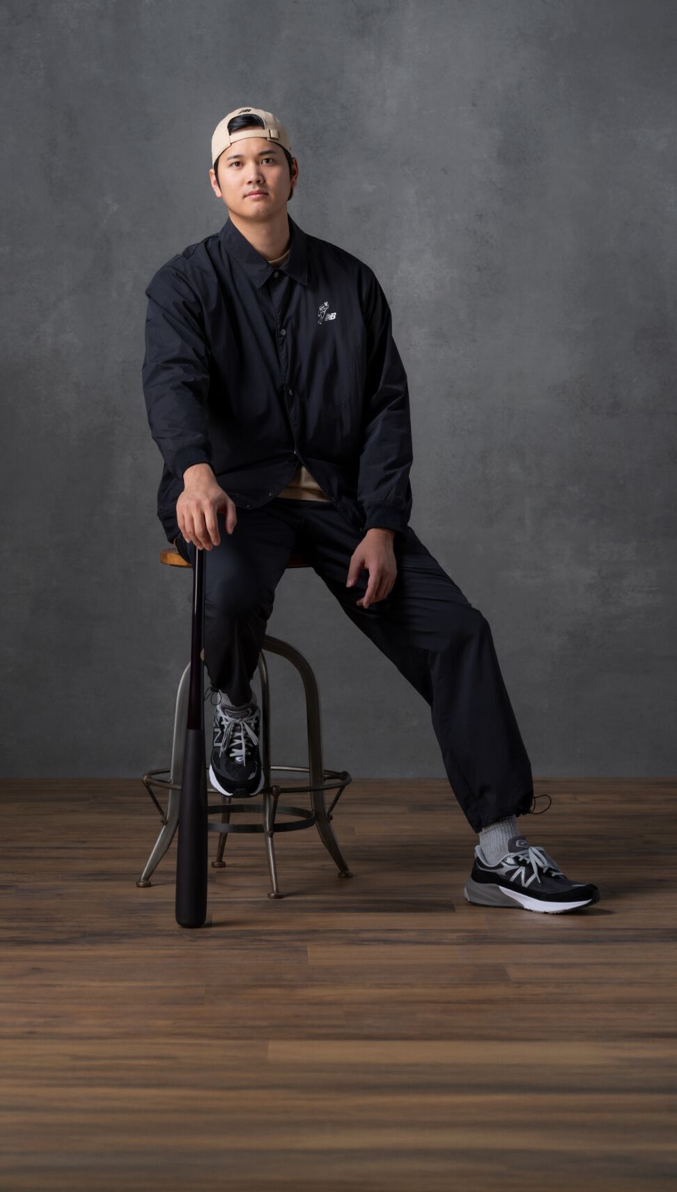 Shohei sitting on a stool in a black outfit.  