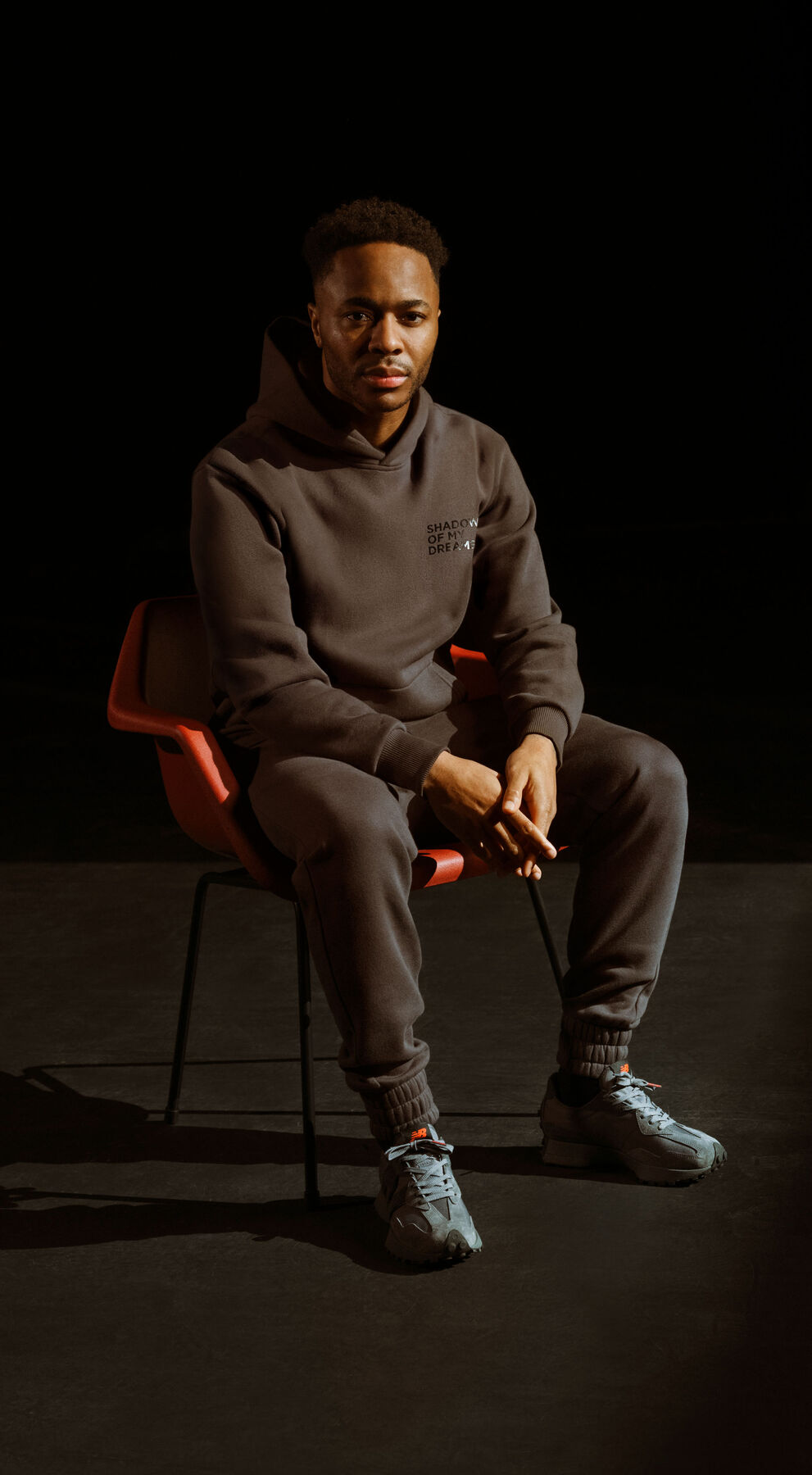 Raheem Sterling sitting in a chair wearing Shadow of My Dreams apparel