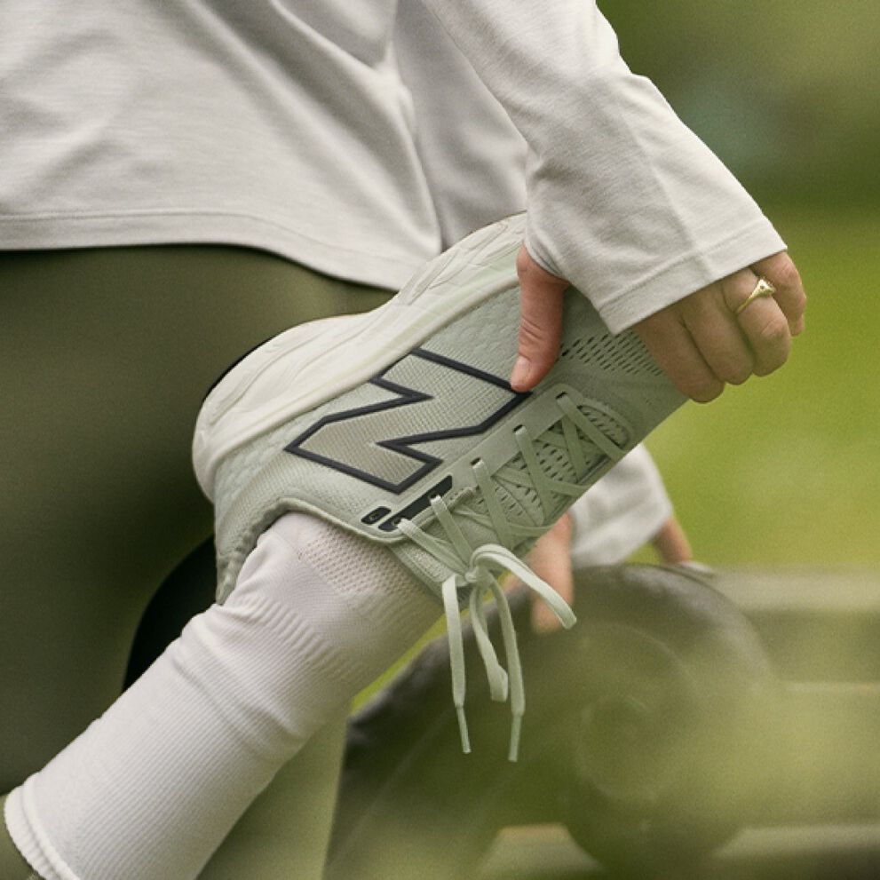 Woman pictured stretching outdoors in New Balance apparel and shoes, including the Fresh Foam X 860v14.