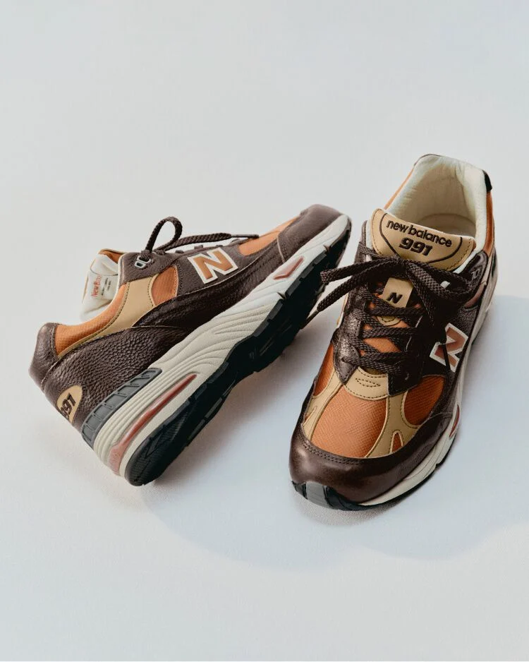 A New Balance Made in UK sneaker in a white studio environment next to sewing thread and fabric shears.