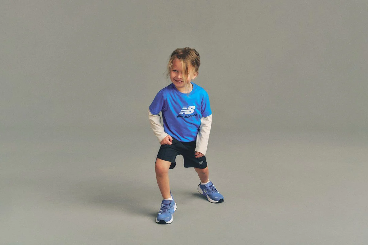 Imagen de estudio en primer plano de un ni&ntilde;o sosteniendo un bal&oacute;n de f&uacute;tbol azul, blanco y morado por encima de la cabeza con ambas manos.