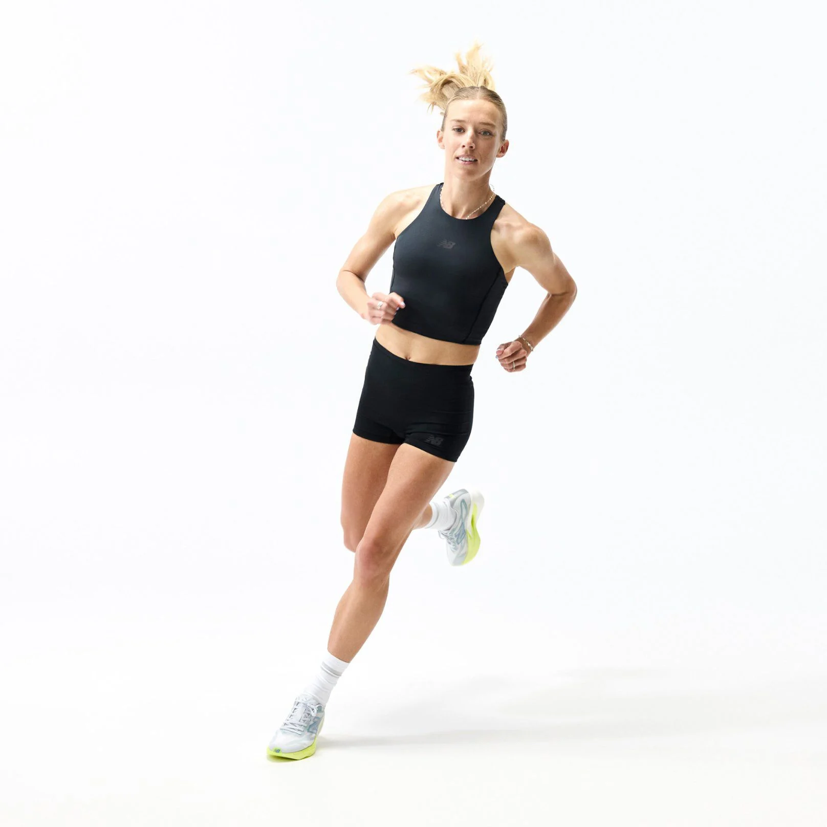 Person running in a studio wearing a black athletic outfit and light gray New Balance running shoes with lime-green soles, shown alongside a close-up of the shoe&rsquo;s cushioned midsole design.