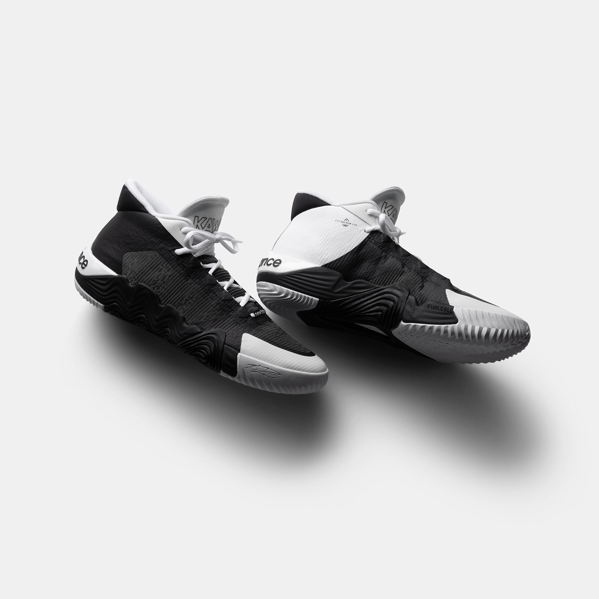 Pair of white and black basketball shoes sitting on a grey background.