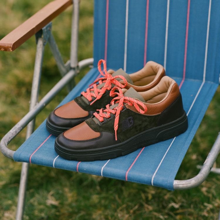 A pair of Drakes’s x New Balance shoes on a folding chair.