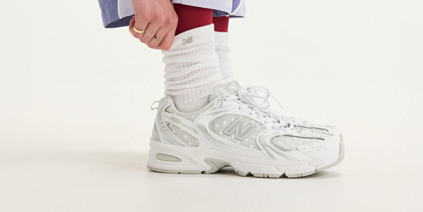 Side view of someone wearing white New Balance sneakers.