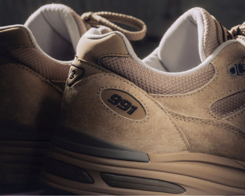 Un par de zapatillas New Balance Made in UK en un estudio de color beige.