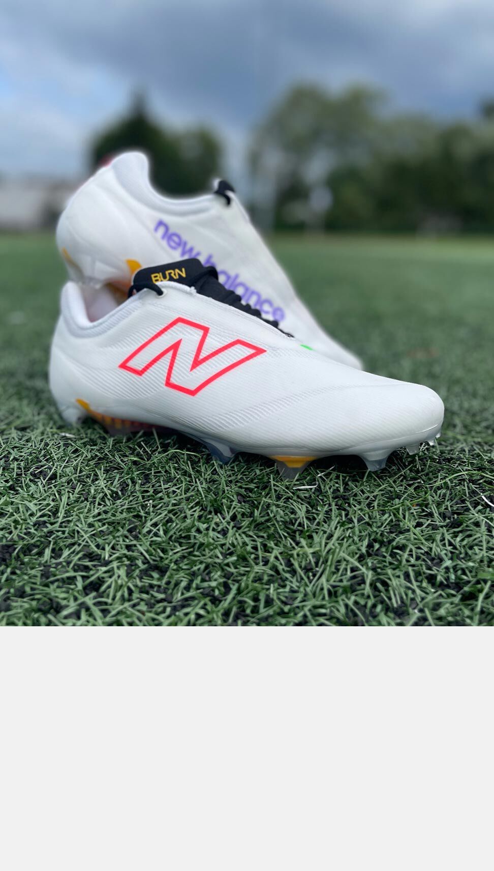 A pair of BurnX4 cleats stacked on each other on a field. 