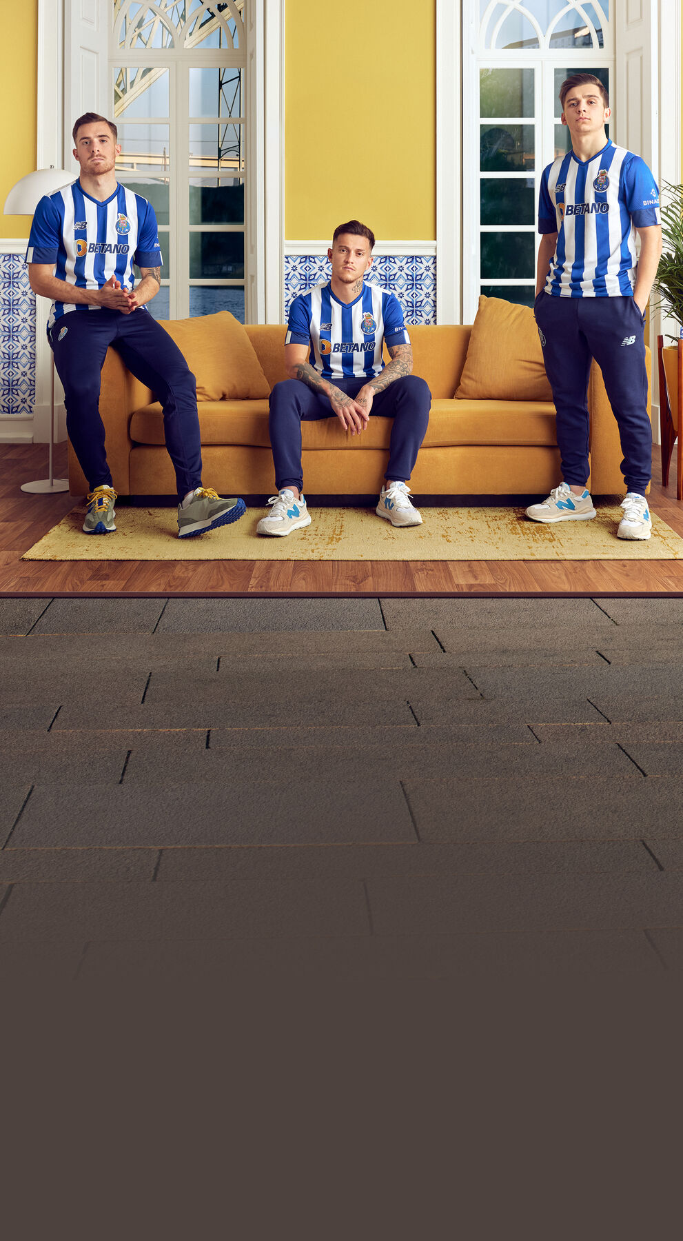  Three soccer athletes sitting on a yellow couch in blue uniforms.    