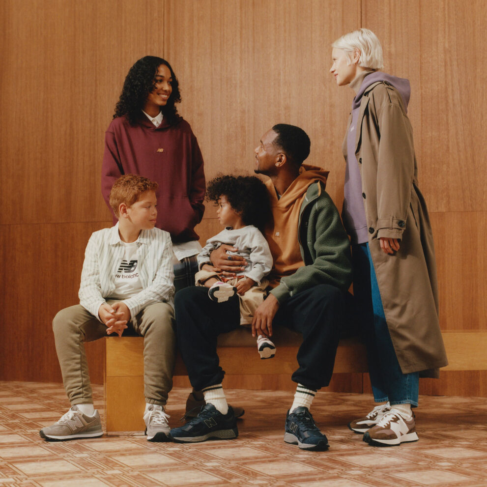 A group of people wearing New Balance clothing gather around a bench. 