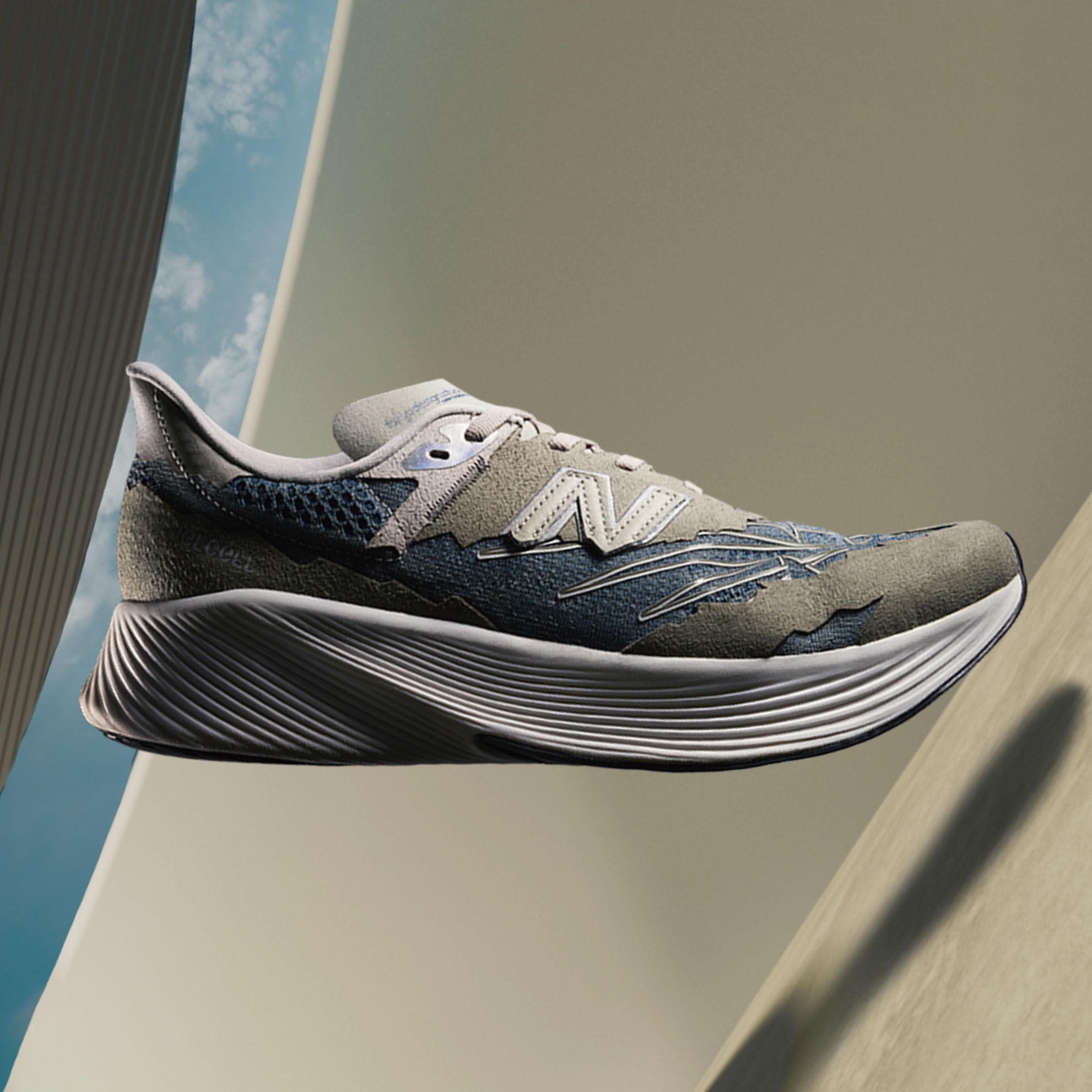 A steel grey NB x Tokyo Design Studio RC Elite running shoe floating in space in front of a 3D rendered architectural background and blue sky