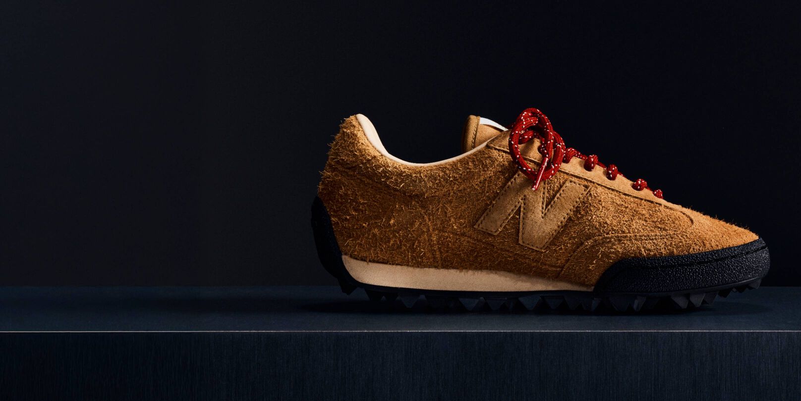 A brown suede Gator Run shoe on a black background.