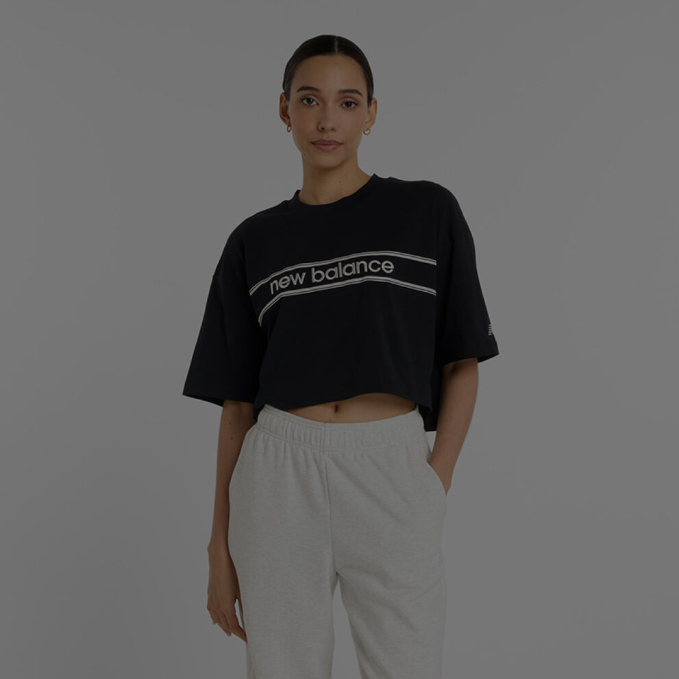 Woman wearing black New Balance shirt and grey New Balance joggers.