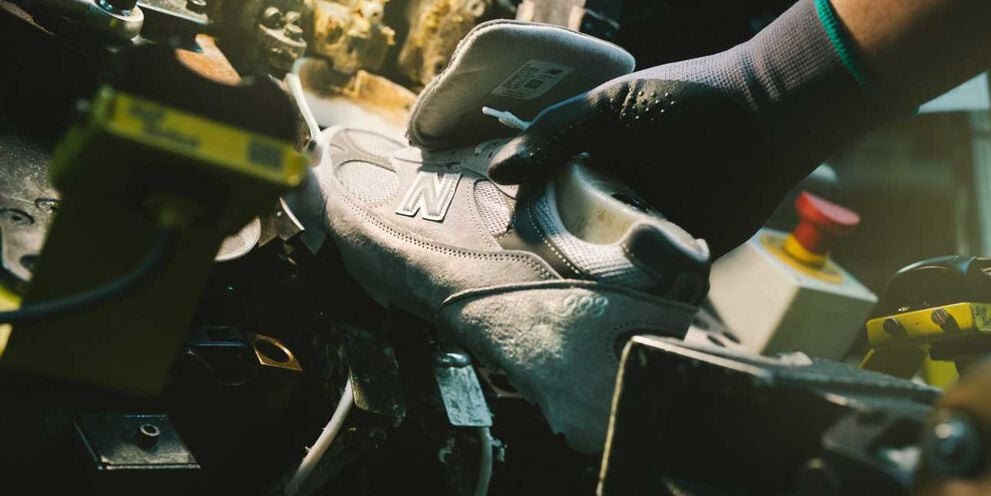 A hand putting a shoe in a device in a factory environment.