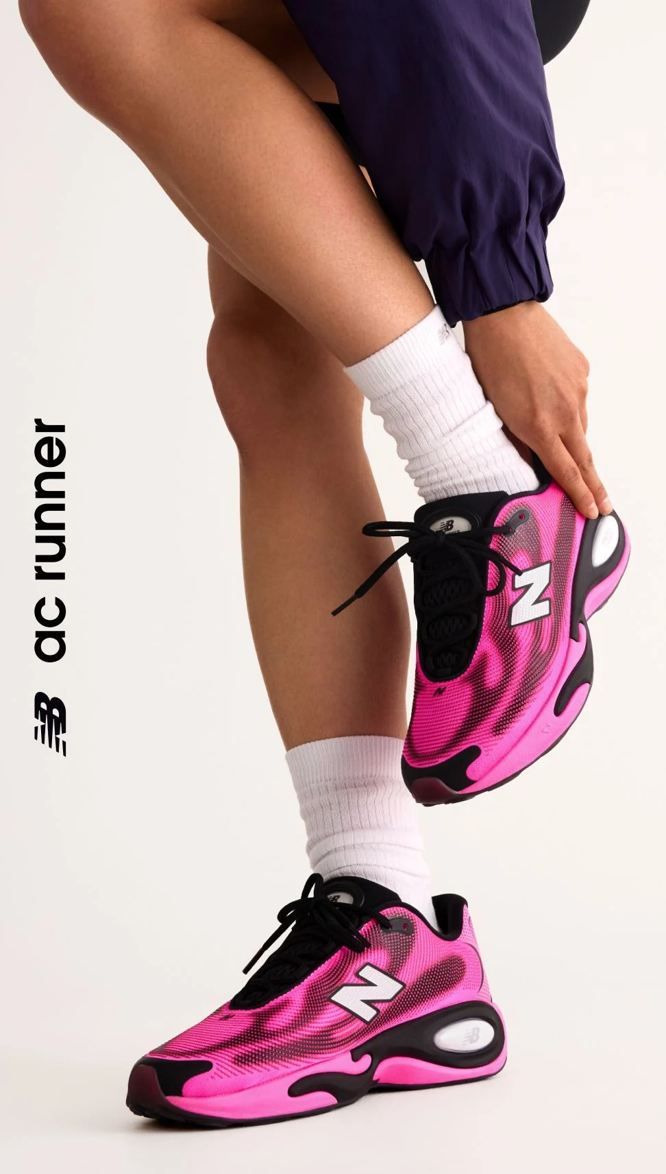 Knee down angle of a person wearing pink AC Runner shoes. 