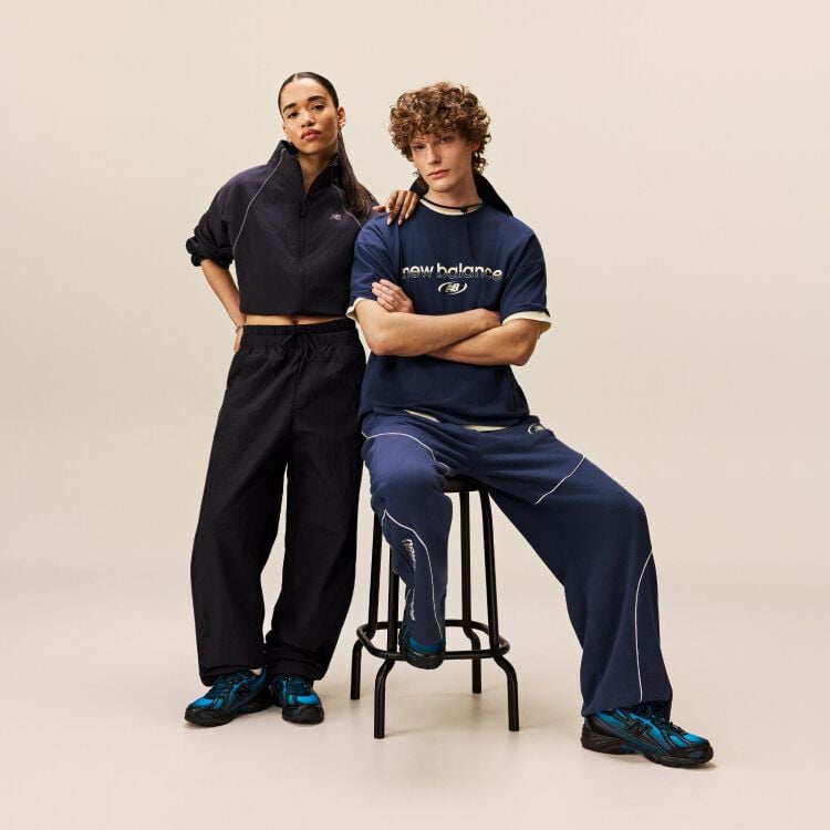 Man sitting down while woman is standing with her arm rested on his shoulder. 