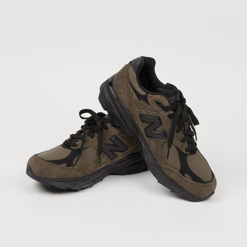 Pair of brown 990v3 shoes posed against a grey studio background
