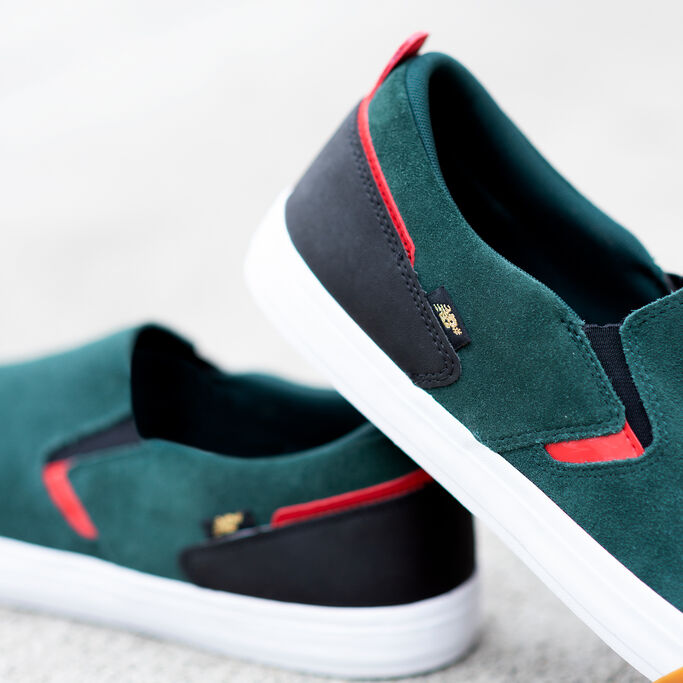 Close in look at the side of the green shoe that is propped up on the other one.