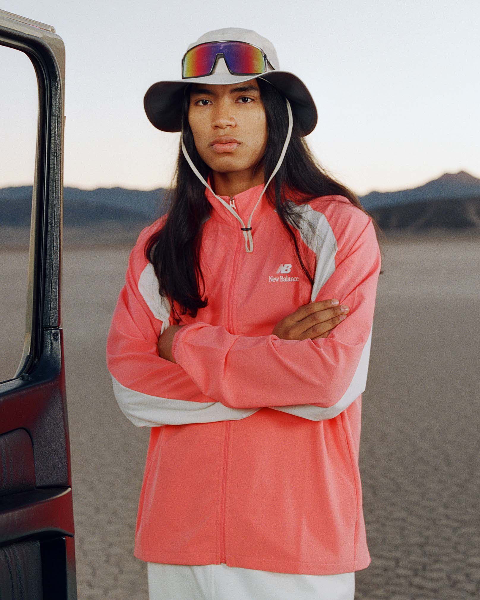 Man crossing his arms wearing a bucket hat with an orange jacket 