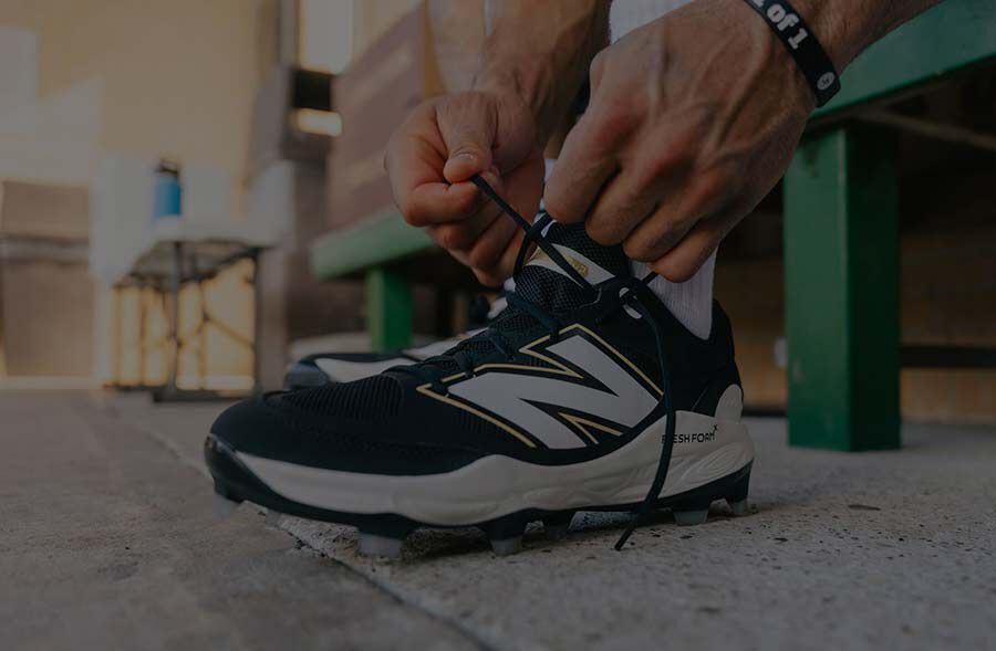 Baseball athlete tying his cleats in a dugout. 