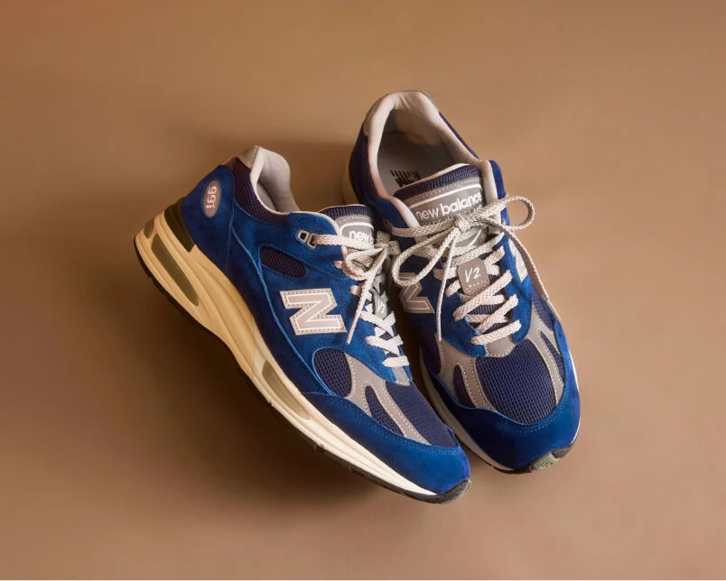 Un par de zapatillas New Balance Made in UK en un estudio de color beige.