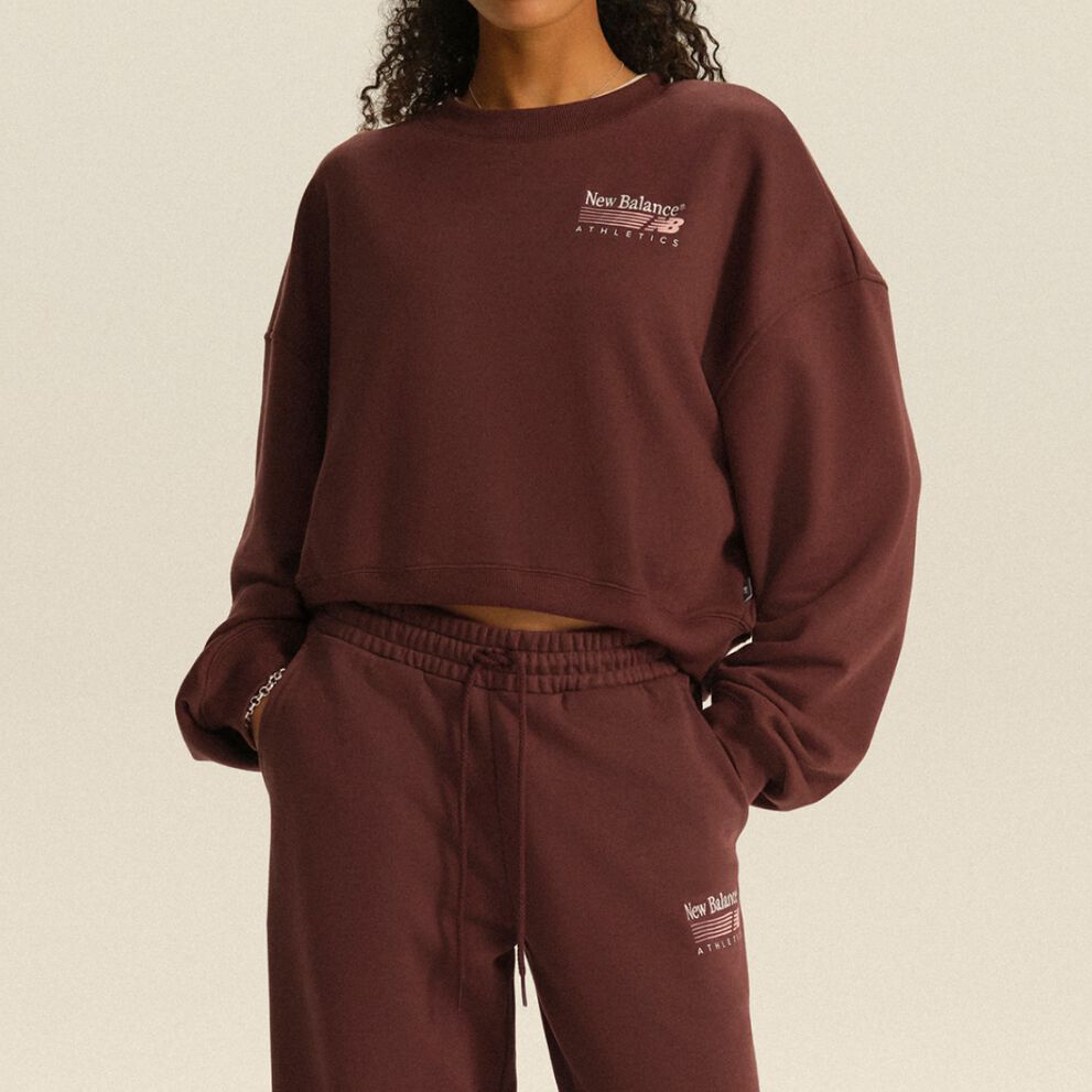 Person wearing a burgundy New Balance Athletics sweatshirt and matching joggers in a clean studio setting.