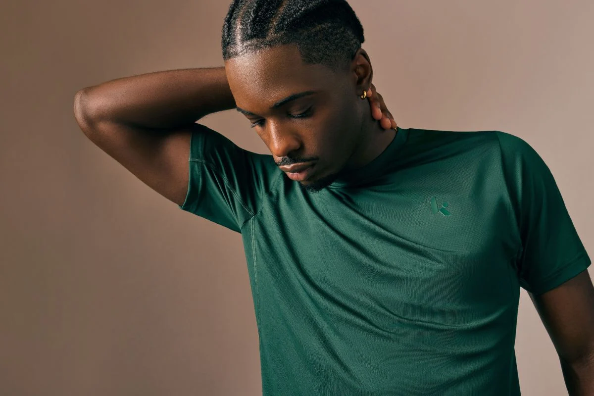 Young man in a green shirt looking at the ground.